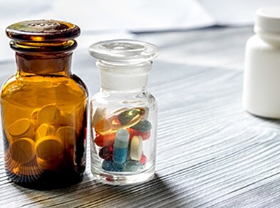 Vitamins and supplements. Pills and pill bottle on grey wooden table background copyspace